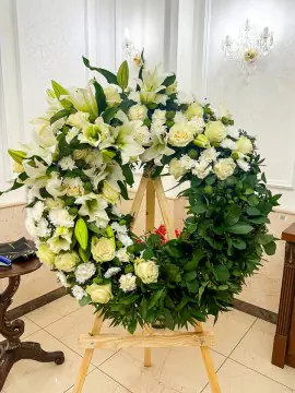 Coroană din flori vii: liliac, trandafir, crizantemă, garoafă, fistic, chică, ruscus · Diametru 70 / 90 cm